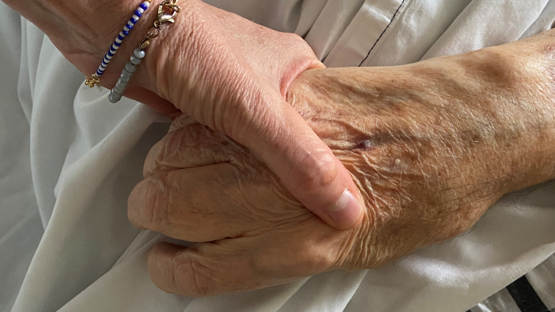 Hand holding on hospital bed