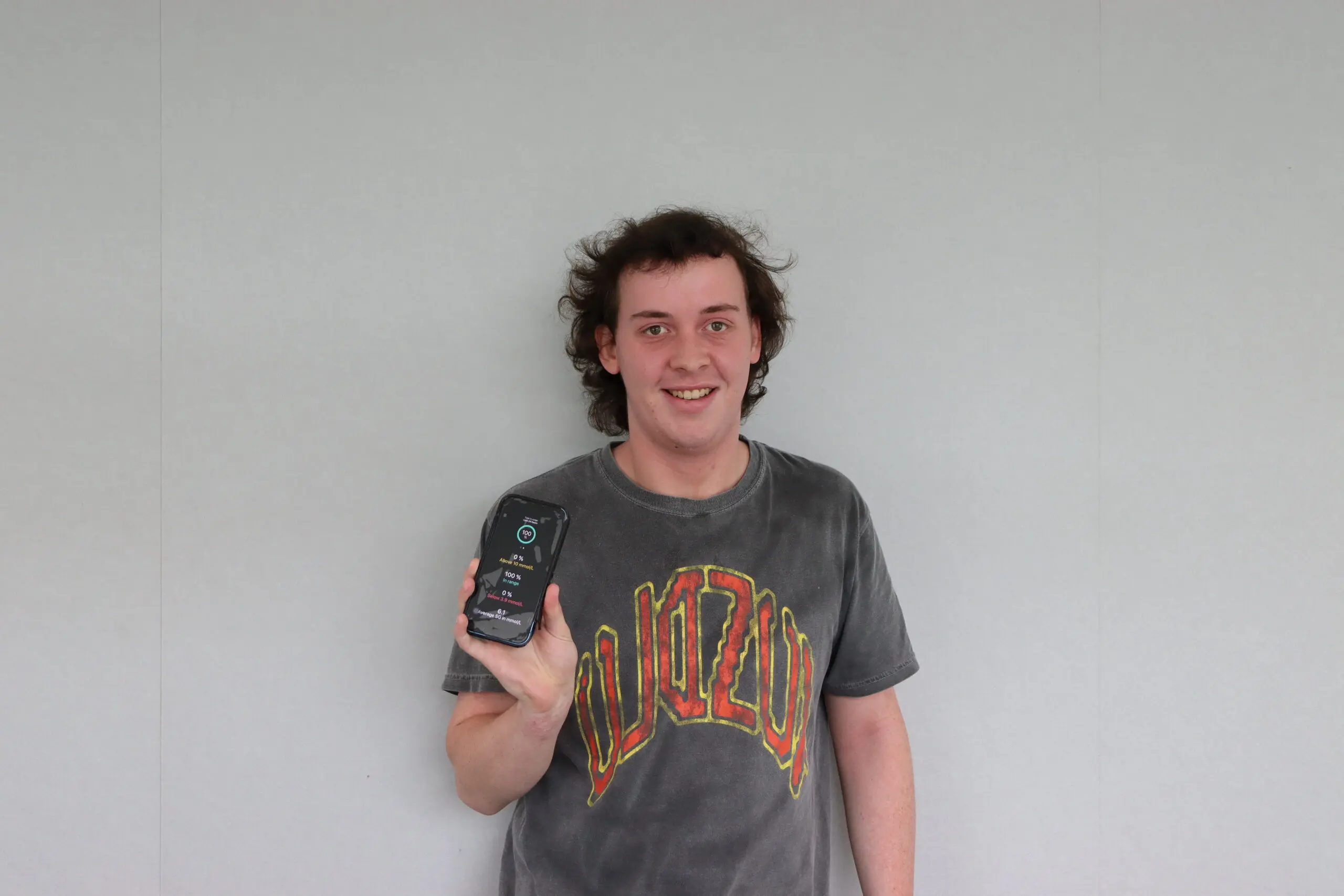 Young man holding a mobile phone showing his diabetes management app