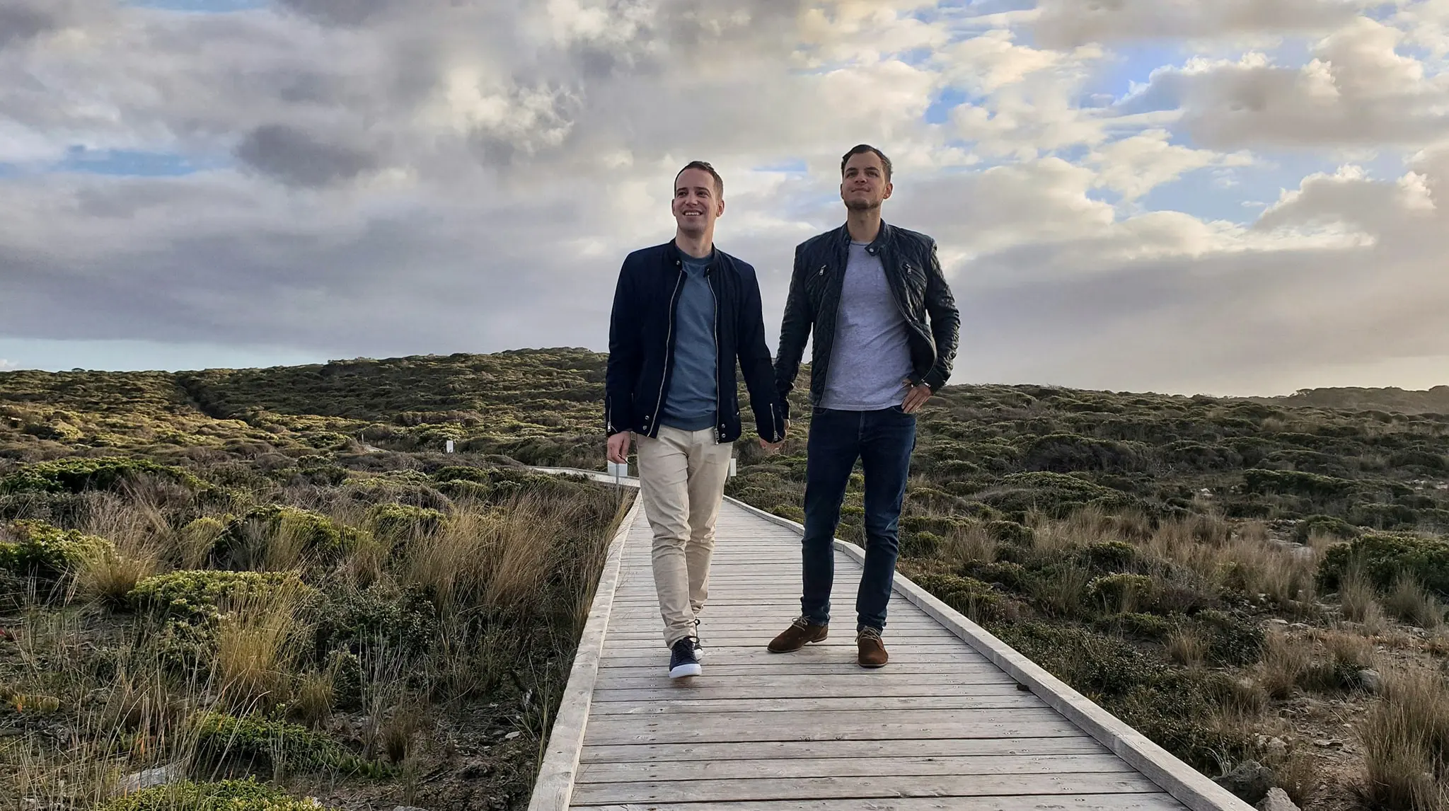 Two man holding hands on a boardwalk