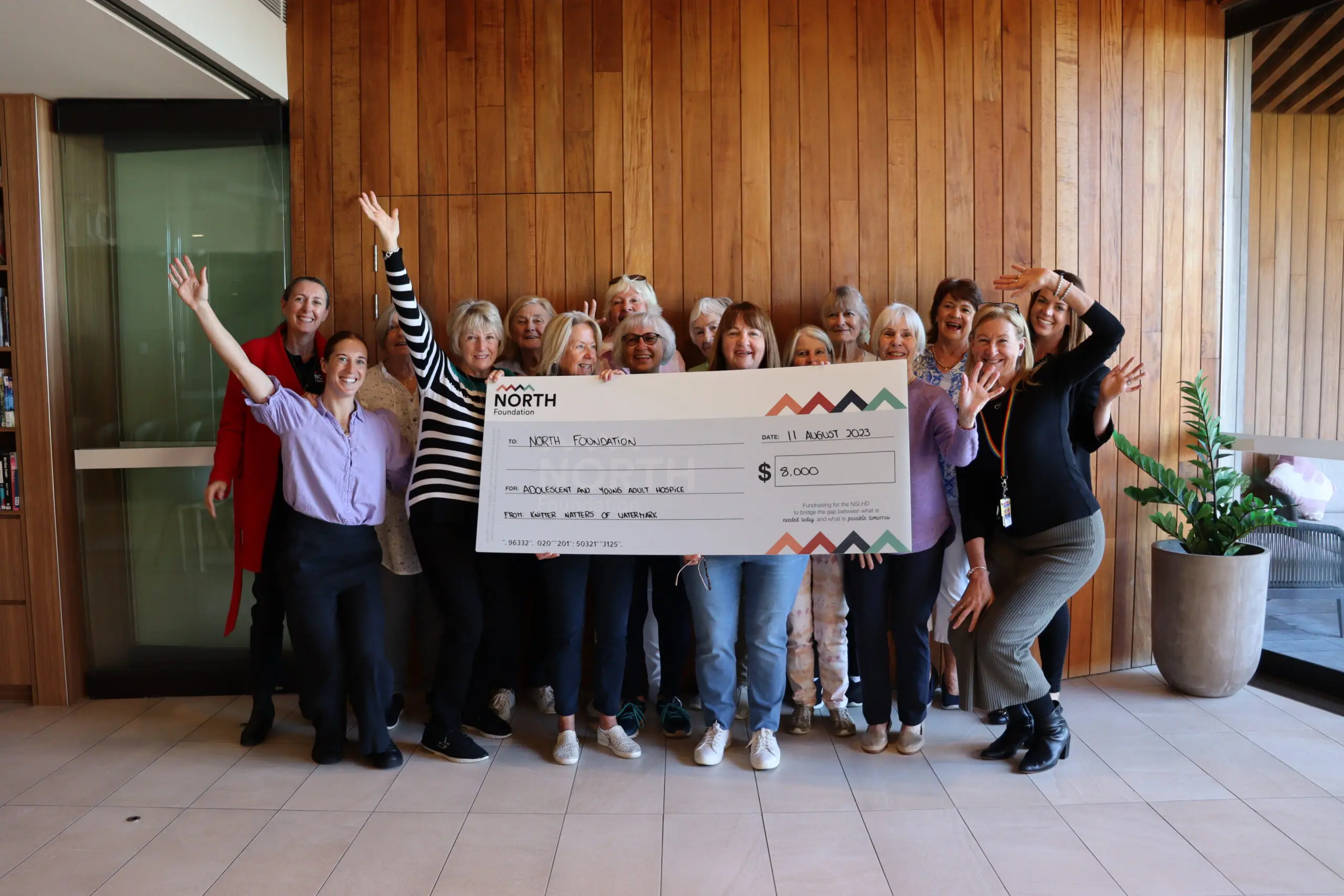 The Knitters & Natters of Watermark holding giant cheque of the amount they fundraised
