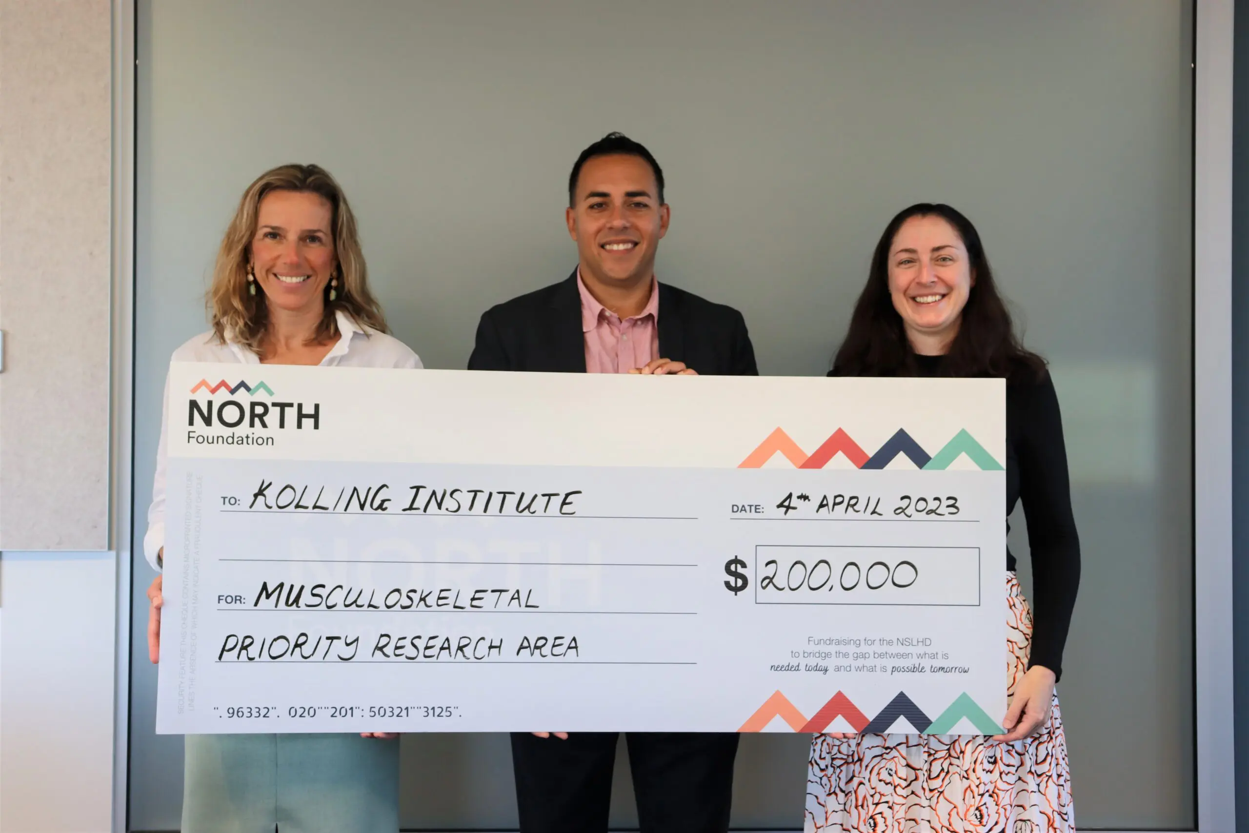 Two ladies and one man holding a $200,000 cheque towards musculoskeletal research