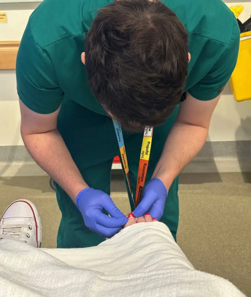 Male doctor removing nail polish on infected toe