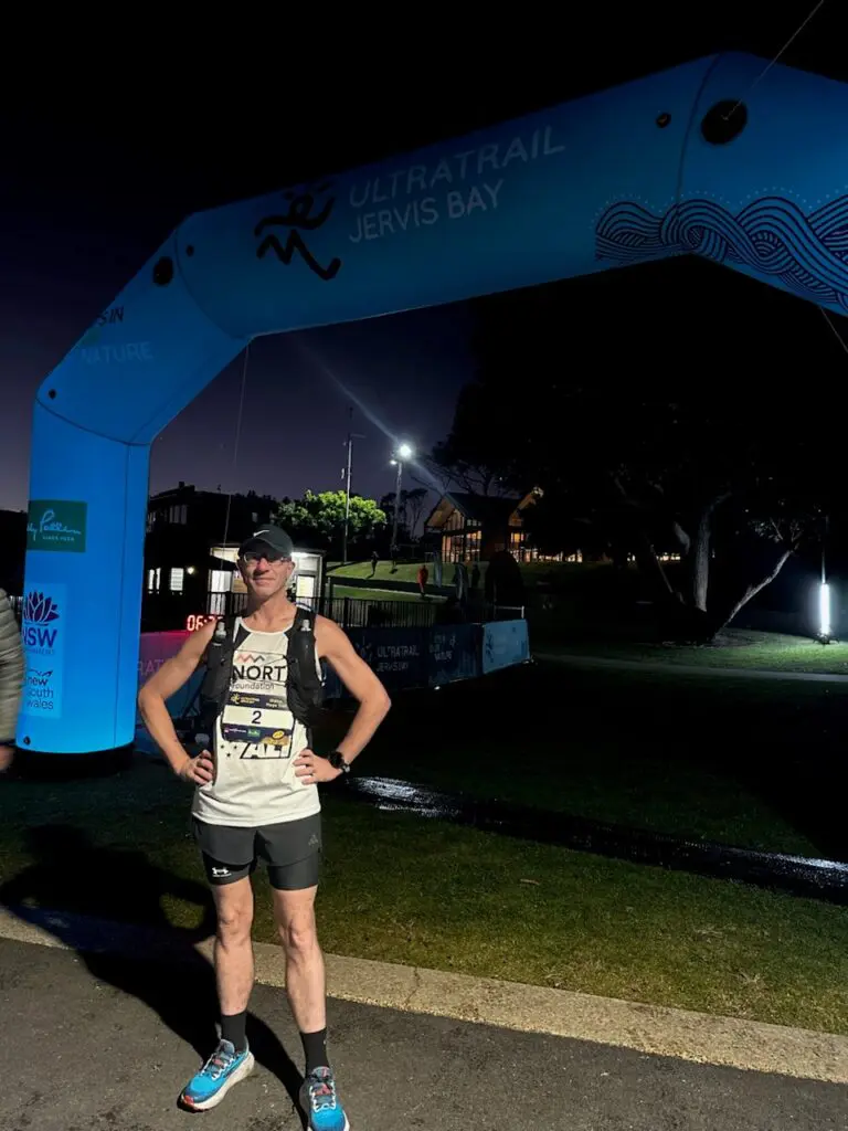 Man smiling standing at race finish line