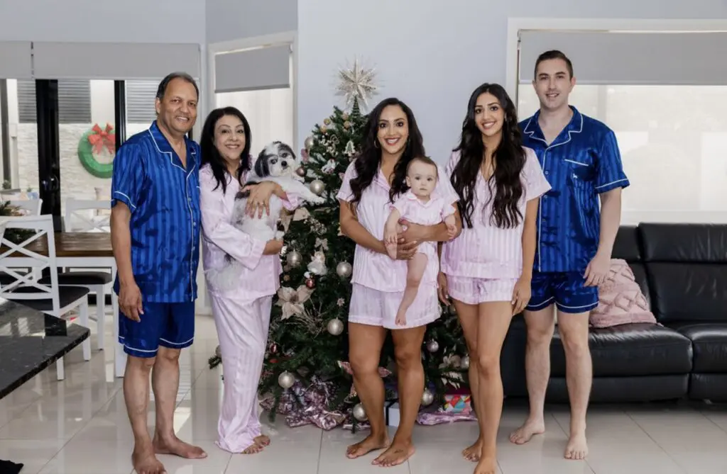 Family photo - two males, three females and a child in front of Christmas tree