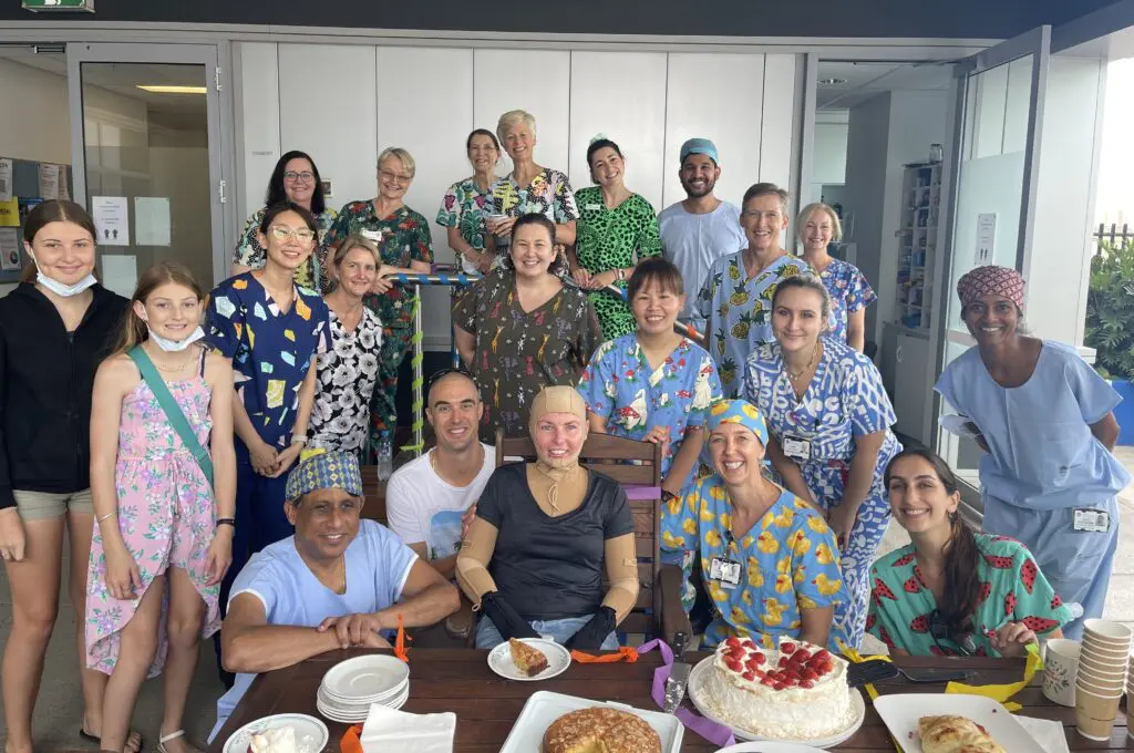 Woman in a compression suit surrounded by healthcare staff in the Severe Burns Injury Unit