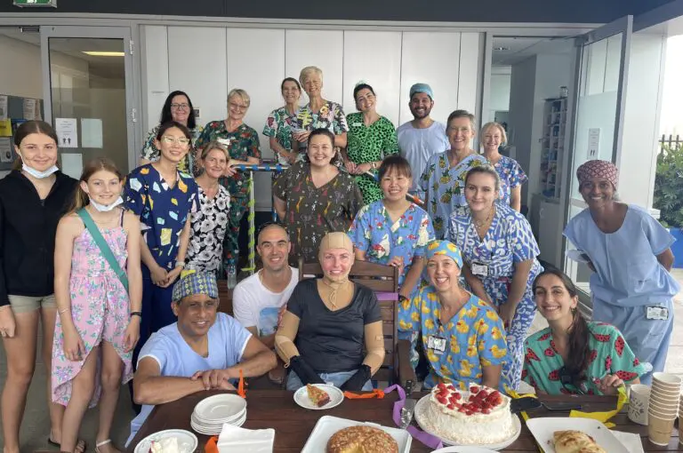 Woman in a compression suit surrounded by healthcare staff in the Severe Burns Injury Unit