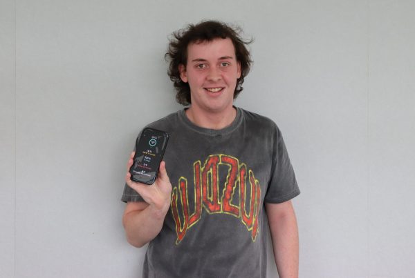 Young man holding a mobile phone showing his diabetes management app