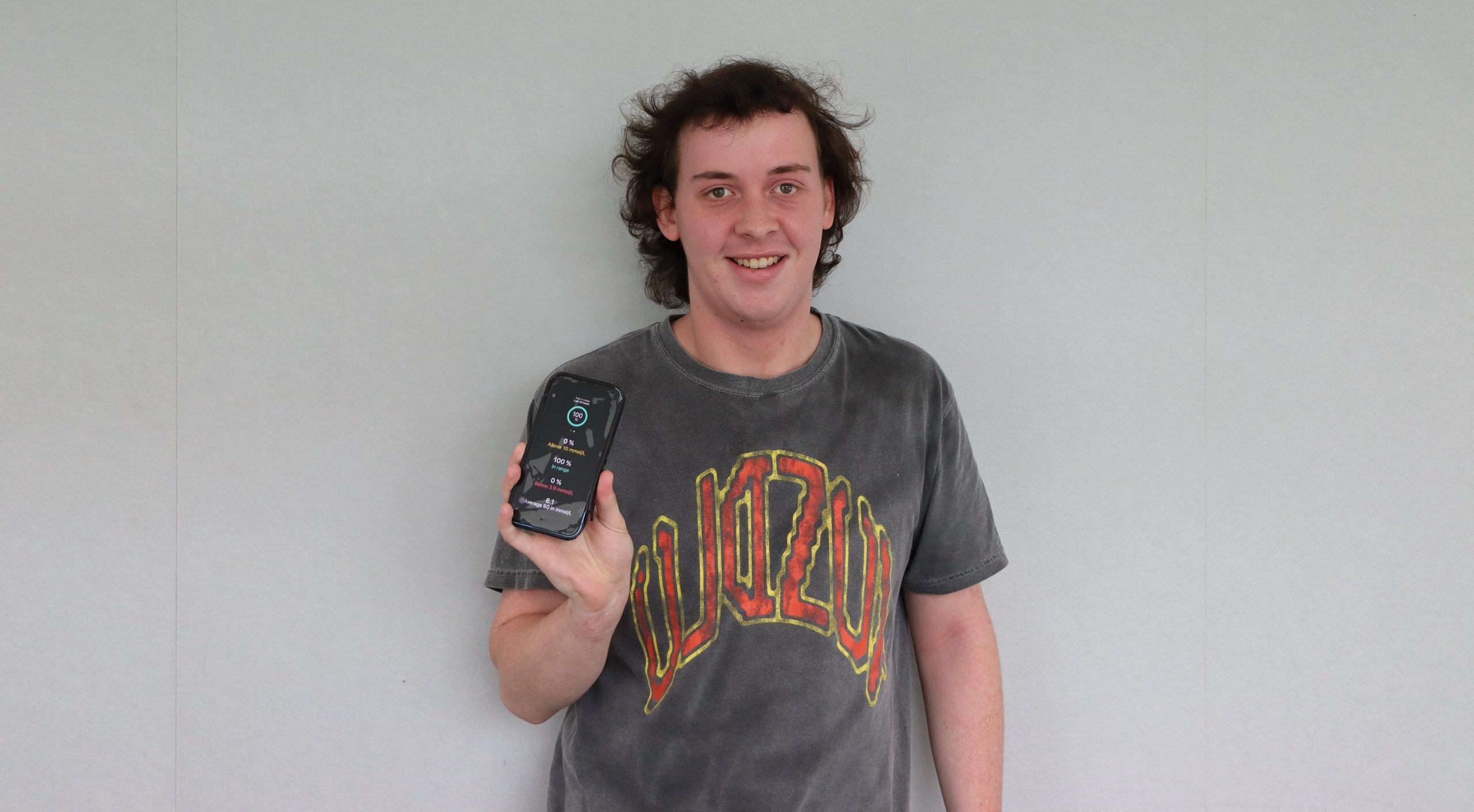 Young man holding a mobile phone showing his diabetes management app