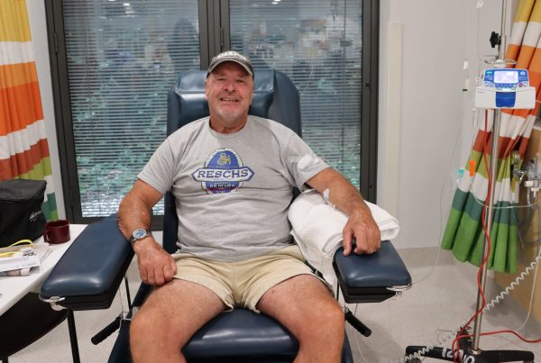 A man in a hospital chair smiling