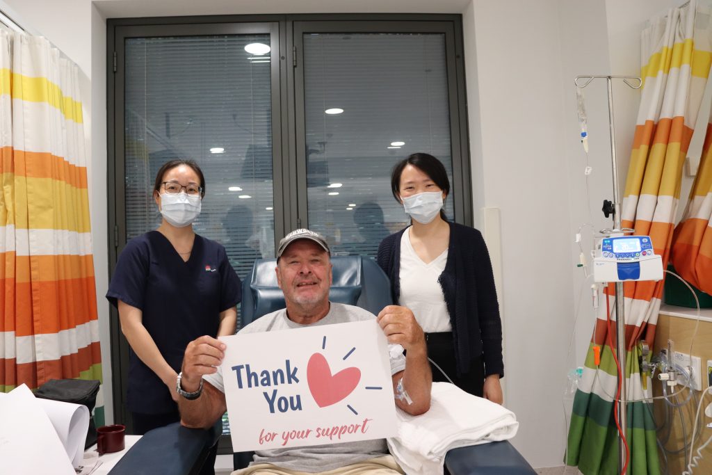 A man in a hospital chair with two asian ladies 