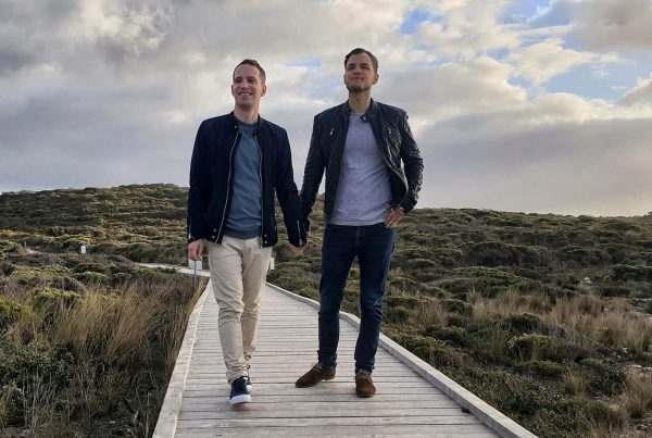 Two man holding hands on a boardwalk