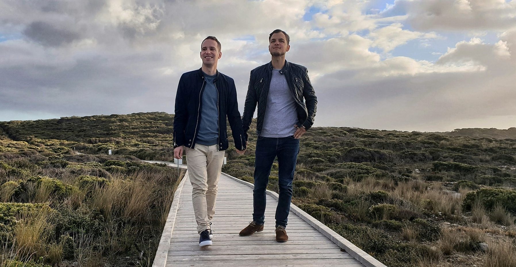 Two man holding hands on a boardwalk