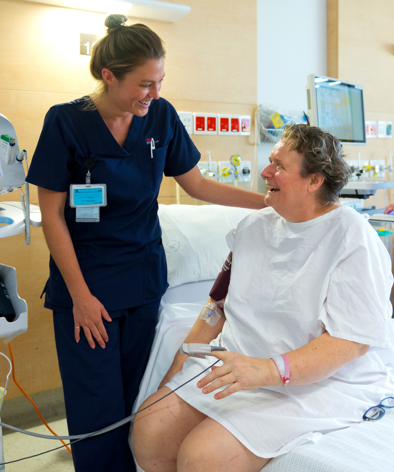 Female nurse smiling to female patient in hospital
