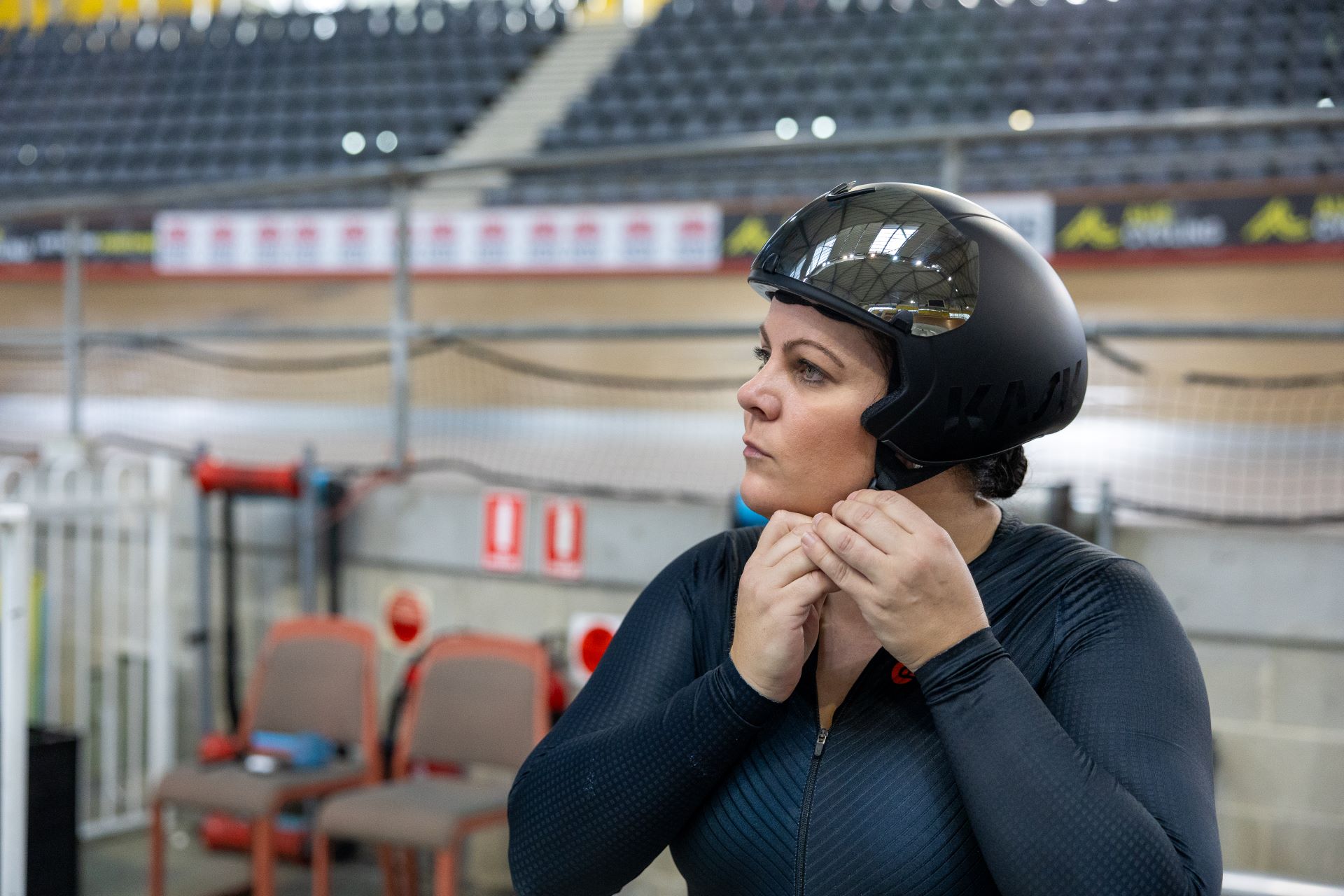 Woman on cycling track putting helmet on